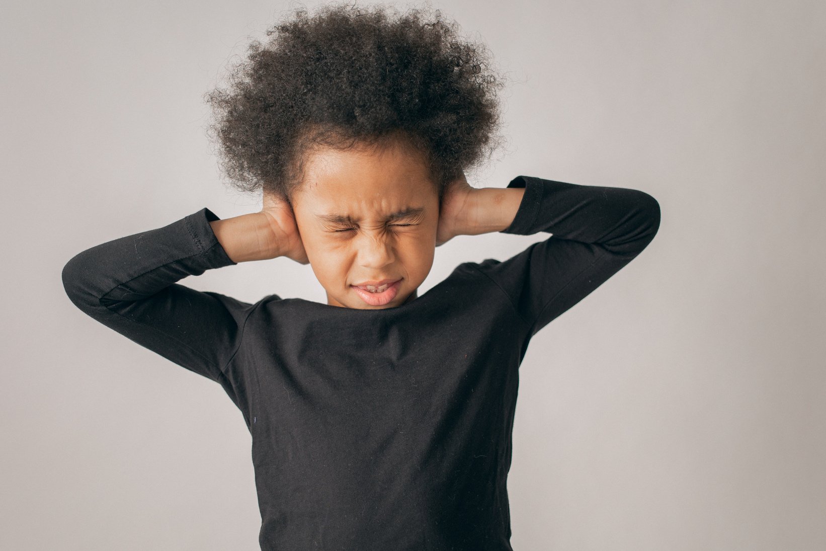 Stressed black girl covering ears